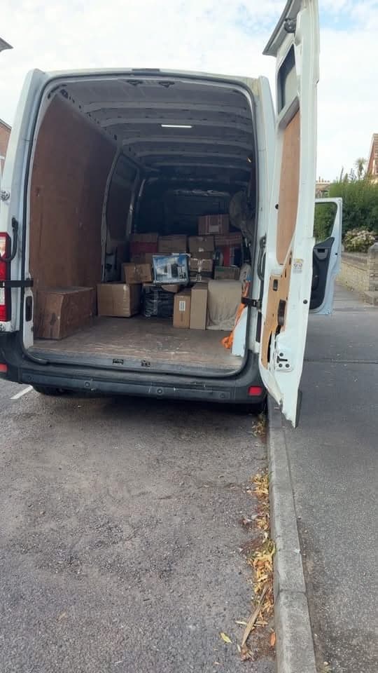 The back of a van open on a street, packed with boxes