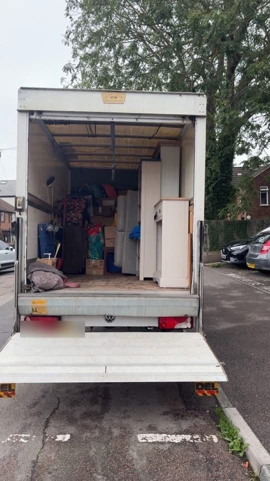 A tail-lift van loaded with wardrobes, cabinets and boxes
